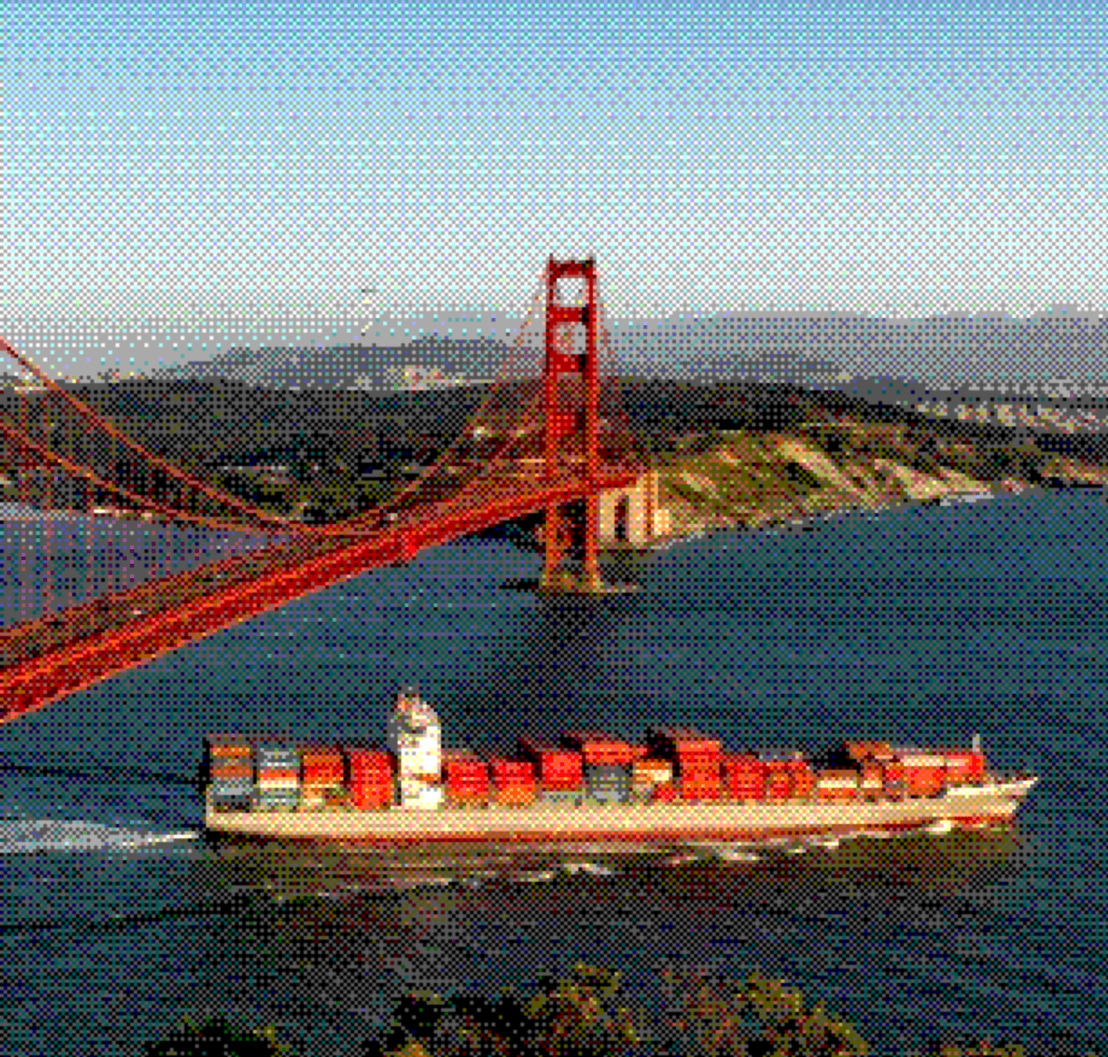 Container ship sailing past a red suspension bridge