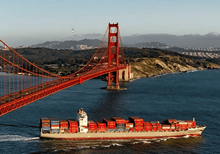 Logistics & transportation Cargo ship sailing under a suspension bridge