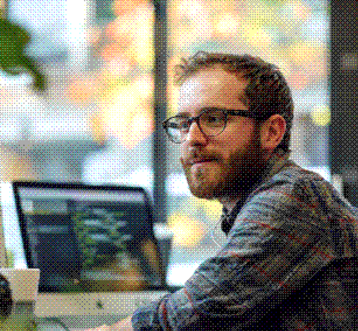 Developer reviewing code on a monitor in a bright office